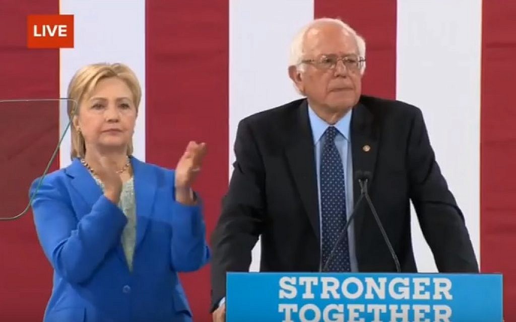 Hillary Clinton looks on as Bernie Sanders endorses her for US president, at a rally in New Hampshire on July 12, 2016 (screen capture: YouTube)