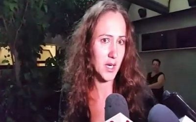 Marina Sarkov talks to reporters from the hospital where her mother was being treated for wounds sustained in a stabbing attack in Netanya on June 30, 2016 (screen capture: Channel 2)