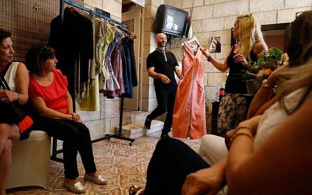 Palestinian American fashion designer Rami Kashou smiles as a Palestinian woman chooses one of his designs during a fitting session at a pop-up shop in the West Bank city of Ramallah on July 27, 2016. (Abbas Momani/AFP)