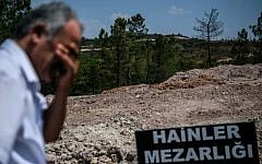 A man stays next to a sign reading in Turkish language  "Traitors' Cemetery" is seen in front of unmarked graves built specially by Istanbul municitality for the dead failed coup soldiers on July 28,2016. (AFP PHOTO / OZAN KOSE)