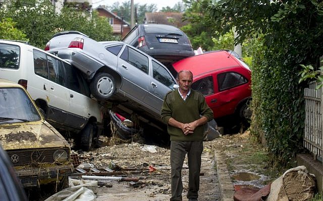 A man passes damaged vehicles in the village of Stajkovci, near Skopje, on August 7, 2016, following overnight torrential rains and fierce storms. (AFP / Robert ATANASOVSKI)