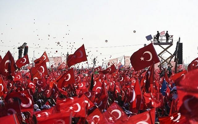 Demonstrators wave Turkish national flags as they stand in front of giant screens and Turkish special force police officers standing guard during a rally against failed military coup, in Istanbul, August 7, 2016. (AFP/BULENT KILIC)