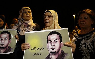 The mother (C) of Palestinian prisoner Bilal Kayed (portrait), demonstrates against administrative detention and in support of her son outside the Ashkelon hospital where he is being held on August 9, 2016. (AFP PHOTO / AHMAD GHARABLI)