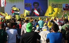 Young men hold Lebanese national flags and yellow flags of the Lebanese Shiite terror group Hezbollah as they watch its leader Hassan Nasrallah deliver a speech on a screen in the southern Lebanese town of Bint Jbeil on August 13, 2016 during a commemoration marking the tenth anniversary of the end of the Second Lebanon War. (AFP Photo/Mahmoud Zayyat)