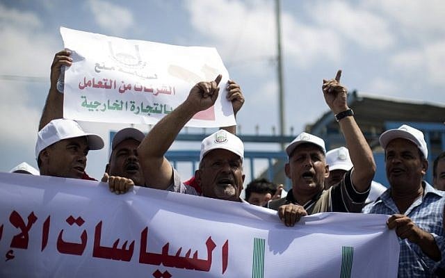 Palestinian businessmen and traders hold banners and shout slogans during a demonstration to protest after Israel suspended their permits to cross to Israel on August 15, 2016 in Beit Hanun, near the Erez crossing point with Israel, in the northern Gaza Strip. / AFP PHOTO / MAHMUD HAMS