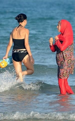 Women, one, wearing a "burkini", a full-body swimsuit designed for Muslim women, walk in the water on Ghar El Melh beach near Bizerte, north-east of the capital Tunis, August 16, 2016. (AFP/FETHI BELAID)