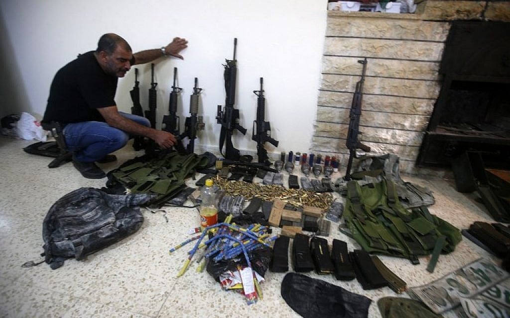 A member of the Palestinian security forces displays weapons at a police station in the West Bank city of Nablus , that the police found on search operation for gunmen who are on the run, August 21, 2016. (AFP/JAAFAR ASHTIYEH)
