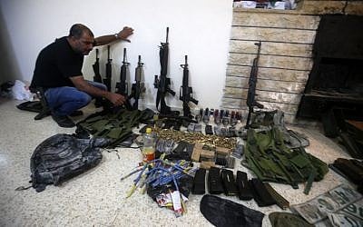 A member of the Palestinian security forces displays weapons at a police station in the West Bank city of Nablus , that the police found on search operation for gunmen who are on the run, August 21, 2016. (AFP/JAAFAR ASHTIYEH)