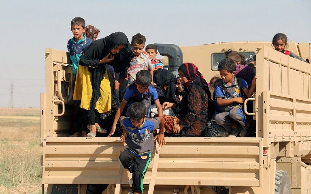 Iraqi displaced families step down from a truck upon their arrival in an area controlled by the Peshmerga forces, some 55 kilometers west of Iraqi city of Kirkuk, on August 21, 2016 after they left their northern village of Hawija to escape from Islamic State group jihadists. (AFP /Marwan IBRAHIM)