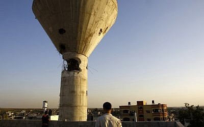 Palestinians look at a water tower that was first damaged during the 2014 Gaza war and appears to have again been struck by Israeli fire on August 21, 2016 in Beit Hanun in the northern Gaza Strip. (AFP PHOTO / MOHAMMED ABED)