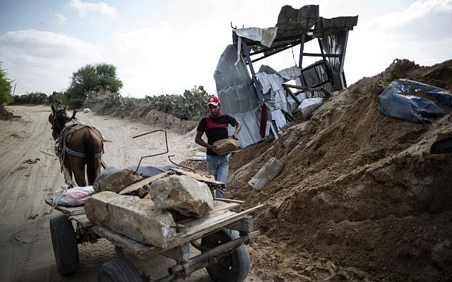 A Palestinian man loads stones on a cart next to a crater in Beit Lahia in the northern Gaza Strip on August 22, 2016, following an Israeli airstrike the night before that targeted Hamas positions in response to a rocket fired from the Palestinian enclave that hit the Israeli city of Sderot. (Mahmud Hams/AFP)