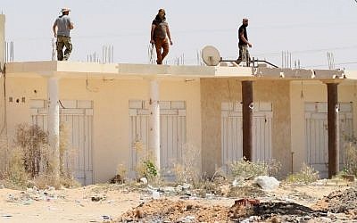Libyan pro-government forces walk on the roof of a building in Sirte as they comb through residential neighborhoods taken from the Islamic State (IS) group on August 22, 2016. (AFP/Mahmud Turkia)