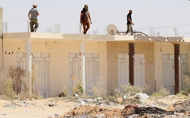 Libyan pro-government forces walk on the roof of a building in Sirte as they comb through residential neighborhoods taken from the Islamic State (IS) group on August 22, 2016. (AFP PHOTO / MAHMUD TURKIA)