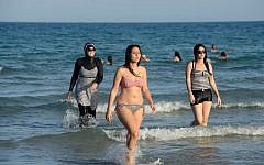 Women on beach with one, left, wearing a burkini, a full-body swimsuit designed for Muslim women. (AFP/FETHI BELAID)