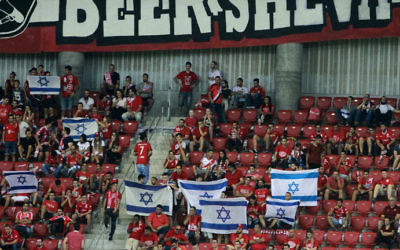 Hapoel Beersheba fans wave Israeli flags before the UEFA Champions League group stages play-off soccer match between Celtic and Hapoel Beersheba at the Turner Stadium in the southern Israeli city of Beersheba on August 23, 2016. (Gil Cohen-Magen/AFP)