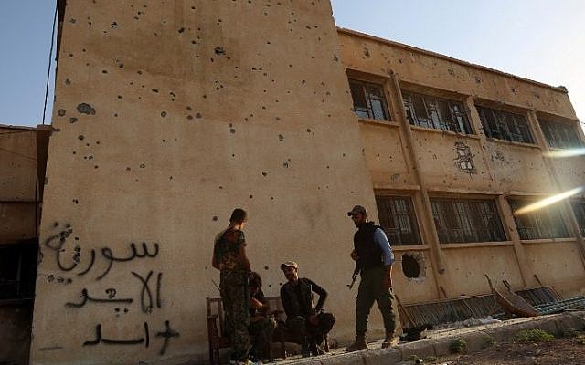 Kurdish fighters belonging to the local police force -- the Asayesh -- and the People's Protection Units (YPG) stand in front of a building covered in bullet holes in the northeastern Syrian city of Hasakeh on August 23, 2016, after they agreed to a truce with regime forces. (Delil Souleriman/AFP) Kurdish fighters belonging to the local police force -- the Asayesh -- and the People's Protection Units (YPG) stand in front of a building covered in bullet holes in the northeastern Syrian city of Hasakeh on August 23, 2016, after they agreed to a truce with regime forces. (Delil Souleriman/AFP)