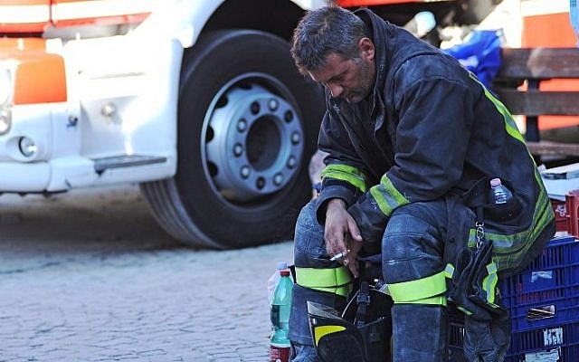 A firefighter takes a rest in the central Italian village of Amatrice, on August 24, 2016 after a powerful earthquake rocked central Italy, killing at least 120 people. (AFP PHOTO/MARCO ZEPPETELLA)