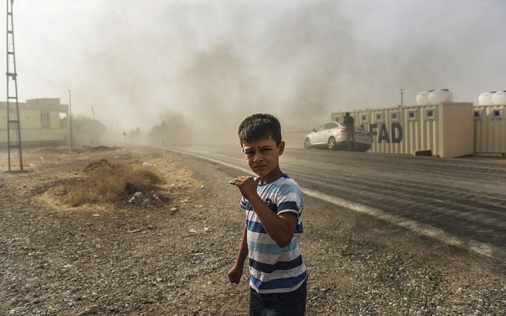 This picture, taken around 5 kilometers west of the Turkish Syrian border city of Karkamis in the southern region of Gaziantep, on August 25, 2016, shows a boy looking on as Turkish Army tanks drive to the Syrian Turkish border town of Jarabulus. (AFP PHOTO / BULENT KILIC)