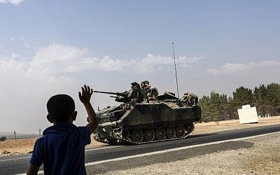 A Turkish boy waves to Turkish tank convoy driving into Syria from the Turkish Syrian border city of Karkamis in the southern region of Gaziantep, on August 26, 2016. AFP  / BULENT KILIC)