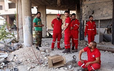 Members of the Red Crescent and a Syrian army soldier gather at the entrance of a damaged building in the government-controlled part of the besieged town of Daraya on August 26, 2016. AFP PHOTO/Youssef KARWASHAN) Members of the Red Crescent and a Syrian army soldier gather at the entrance of a damaged building in the government-controlled part of the besieged town of Daraya on August 26, 2016. AFP PHOTO/Youssef KARWASHAN)