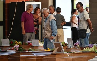 People walk past the coffins of earthquake victims, in a gymnasium arranged in a chapel of rest on August 26, 2016, in Ascoli Piceno, two days after a 6.2-magnitude earthquake struck the region killing 281 people. (AFP PHOTO/ALBERTO PIZZOLI)
