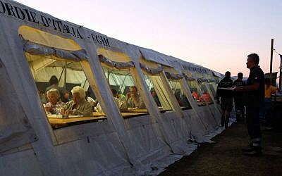 People eat in a tent in the Italian town of Sant' Angelo, near Amatrice, on August 26, 2016, two days after a 6.2-magnitude earthquake struck the region killing 281 people. (AFP PHOTO/MARIO LAPORTA)