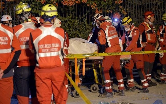 Rescuers of the Italian Red Cross carry the body of a victim on a stretcher in a delimited area in the central Italian village of Amatrice on August 26, 2016, two days after a 6.2-magnitude earthquake struck the region killing some 267 people. AFP / ANDREAS SOLARO)