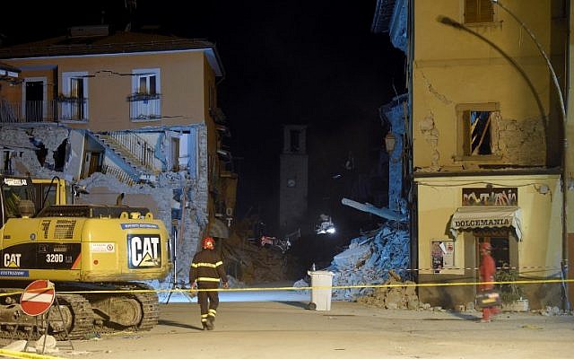 An Italian firefighter walks past the damaged Sant'Agostino church and the rubble of earthquake destroyed buildings in a delimited area in the central Italian village of Amatrice on August 26, 2016, two days after a 6.2-magnitude earthquake struck the region killing 281 people. (AFP PHOTO/ANDREAS SOLARO)