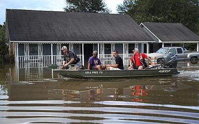 People navigates a boat past a flooded home in Baton Rouge, Louisiana, August 15, 2016. (Joe Raedle/Getty Images/AFP)