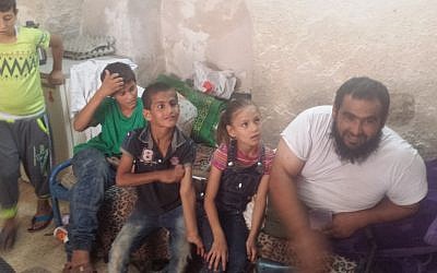 Anwar Burqan, an 8-year-old Palestinian girl whose bicycle was destroyed by two border guards, smiles for a picture along with her father Amer, right, and three of her siblings in their family home in Hebron on August 17, 2016. (Lonny Baskin)