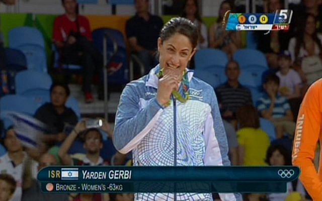 Israeli judoka Yarden Gerbi playfully bites her bronze medal for the women's under-63kg category during the awards ceremony at the Olympic Games in Rio on August 9, 2016 (screen capture: Channel 55)