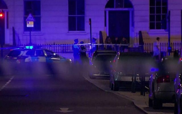 Police officers stand behind cordon tape after a mass stabbing attack in London, Thursday, Aug. 4, 2016. (Sky News via AP)