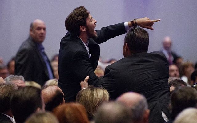 A demonstrator is led away as Republican presidential candidate Donald Trump delivers an economic policy speech to the Detroit Economic Club, Monday, Aug. 8, 2016, in Detroit. (AP Photo/Evan Vucci)