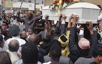 In this Aug. 27, 1991 file photo, the casket of Gavin Cato passes the crowd of mourners outside St. Anthony's Baptist Church in the Brooklyn borough of New York. A plan to mark the 25th anniversary of the Crown Heights riot with a family-friendly street festival has drawn criticism from the brother of a rabbinical student who suffered a fatal knife wound during the unrest. (AP/Joe Major)