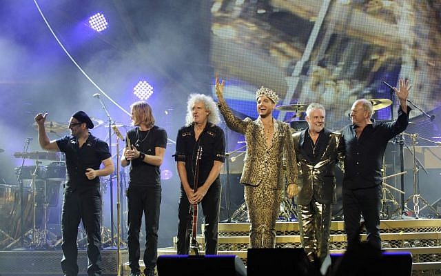 Members of the band Queen with Adam Lambert (in gold lame), standing in for the beloved and deceased Freddie Mercury (Courtesy Queen)