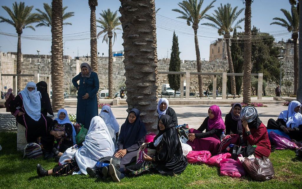 Arab women wait in the shade outside the walls of the Muslim Quarter of Jerusalem's Old City, on August 22, 2016. (Photo by Hadas Parush/Flash90)