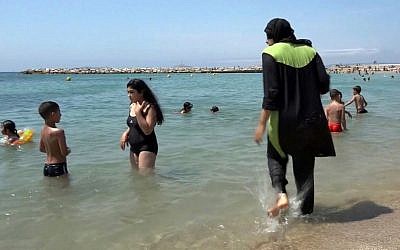 In this Aug. 4 2016 file photo made from video, Nissrine Samali, 20, gets into the sea wearing a burkini, a wetsuit-like garment that also covers the head, in Marseille, southern France. (AP Photo, File)