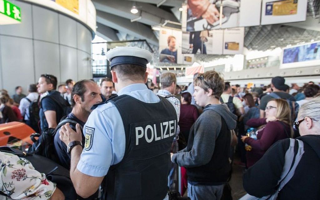 Illustrative: A policeman talks to travelers in the departure area at Frankfurt airport, central Germany (Frank Rumpenhorst/dpa via AP)
