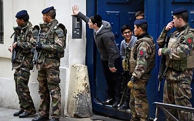 Children peering out from a doorway as armed soldiers patrol outside their school in the Jewish quarter of the Marais district in Paris, France, January 13, 2015. (Jeff J Mitchell/Getty Images/via JTA)