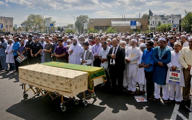 Thousands gather to pray at caskets of Imam Maulama Akonjee, draped in green top, and Thara Uddin in a municipal parking lot, Monday August 15, 2016, in New York. (AP/Bebeto Matthews)