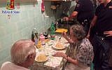 In this recent photo made available by the Italian Police, two police officers serve pasta, after cooking it, to two elderly, after they were called in a Rome neighborhood to check on a couple loudly quarreling on a recent, hot summer night. Police say that four officers who came to the couple's apartment used butter, cheese, spaghetti and "all their humanity" to cook them dinner and ease their loneliness. (Italian Police Photo via AP)