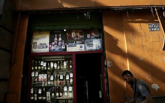 In this Wednesday, Aug. 9, 2016 photo, a man works in front of a shop selling alcohol with prices attached to the bottles on display in downtown Cairo, Egypt. (AP Photo/Nariman El-Mofty)