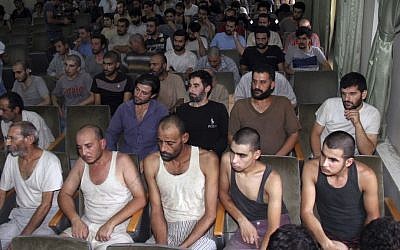 In this Saturday, Sept. 1, 2012, file photo, Syrian prisoners sit in a courtroom before their release in Damascus, Syria. (AP Photo/Bassem Tellawi, File)