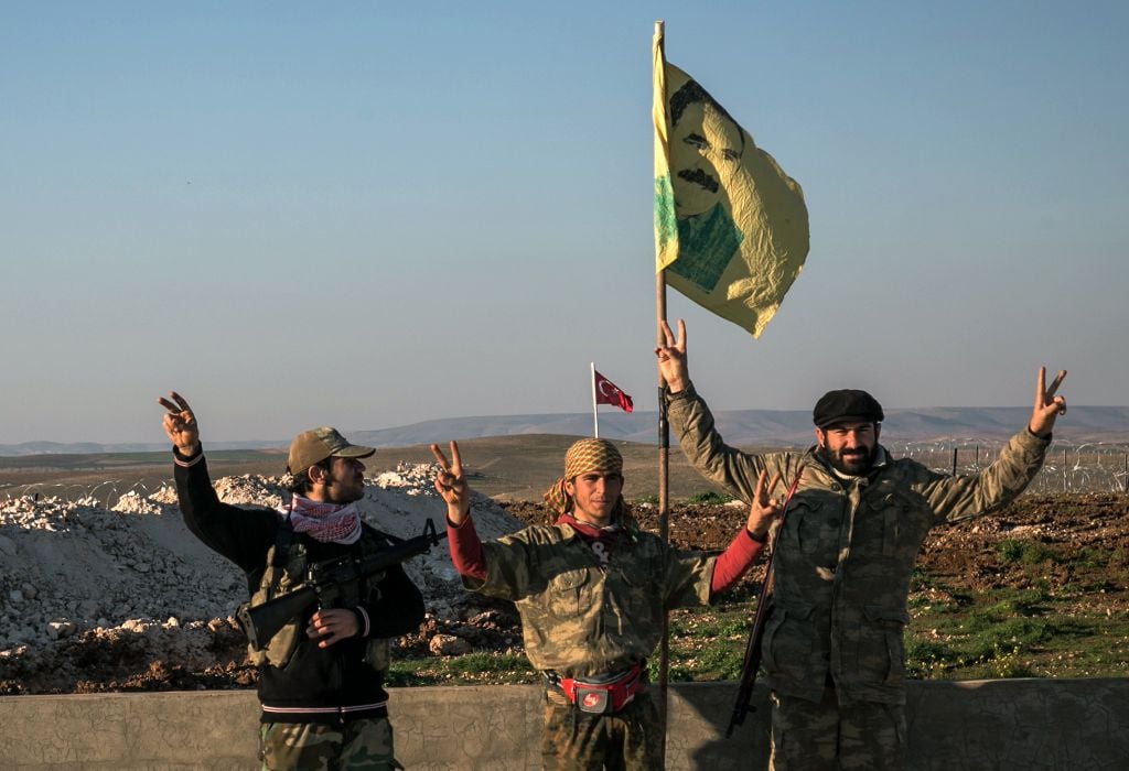 In this Feb. 22, 2015 file photo, Syrian Kurdish militia members of the YPG make a V-sign next to a drawing of Abdullah Ocalan, jailed Kurdish rebel leader, in Esme village in Aleppo province, Syria. (Mursel Coban/Depo Photos via AP) In this Feb. 22, 2015 file photo, Syrian Kurdish militia members of the YPG make a V-sign next to a drawing of Abdullah Ocalan, jailed Kurdish rebel leader, in Esme village in Aleppo province, Syria. (Mursel Coban/Depo Photos via AP)