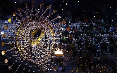 Spectators sit beside the cauldron with the Olympic flame prior to the closing ceremony in the Maracana Stadium at the 2016 Summer Olympics in Rio de Janeiro, Brazil, Sunday, Aug. 21, 2016. (AP Photo/Natacha Pisarenko)