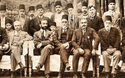 Sir Sassoon Eskell (center, in fez) sits directly on the left of King Faisal I of Iraq (with dark beard) in Baghdad in a photo from the 1920s. (Wikimedia Commons)