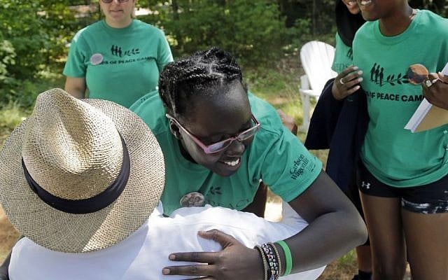 In this Aug. 4, 2016 photo, second-year camper, Ludya, hugs Tim Wilson, special adviser, to the Seeds of Peace camp in Otisfield, Maine. (AP Photo/Elise Amendola) 