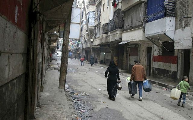In this Feb. 11, 2016, file photo, civilians walk with containers for fuel and water in Aleppo, Syria. (Alexander Kots/Komsomolskaya Pravda via AP, File)