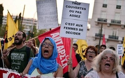 Muslim women march towards the French embassy in Athens holding placards with messages such as "too covered or not enough, it is up to women to decide," in protest at the decision by some French mayors to ban the Islamic burkini swimsuit on their beaches, August 30, 2016, AFP PHOTO / LOUISA GOULIAMAKI