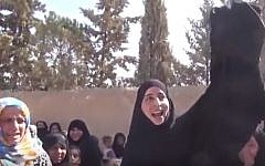 A woman burns a full-body covering in the street as residents celebrate the retreat of Islamic State in Manbij, Syria, August 2016 (YouTube screenshot)
